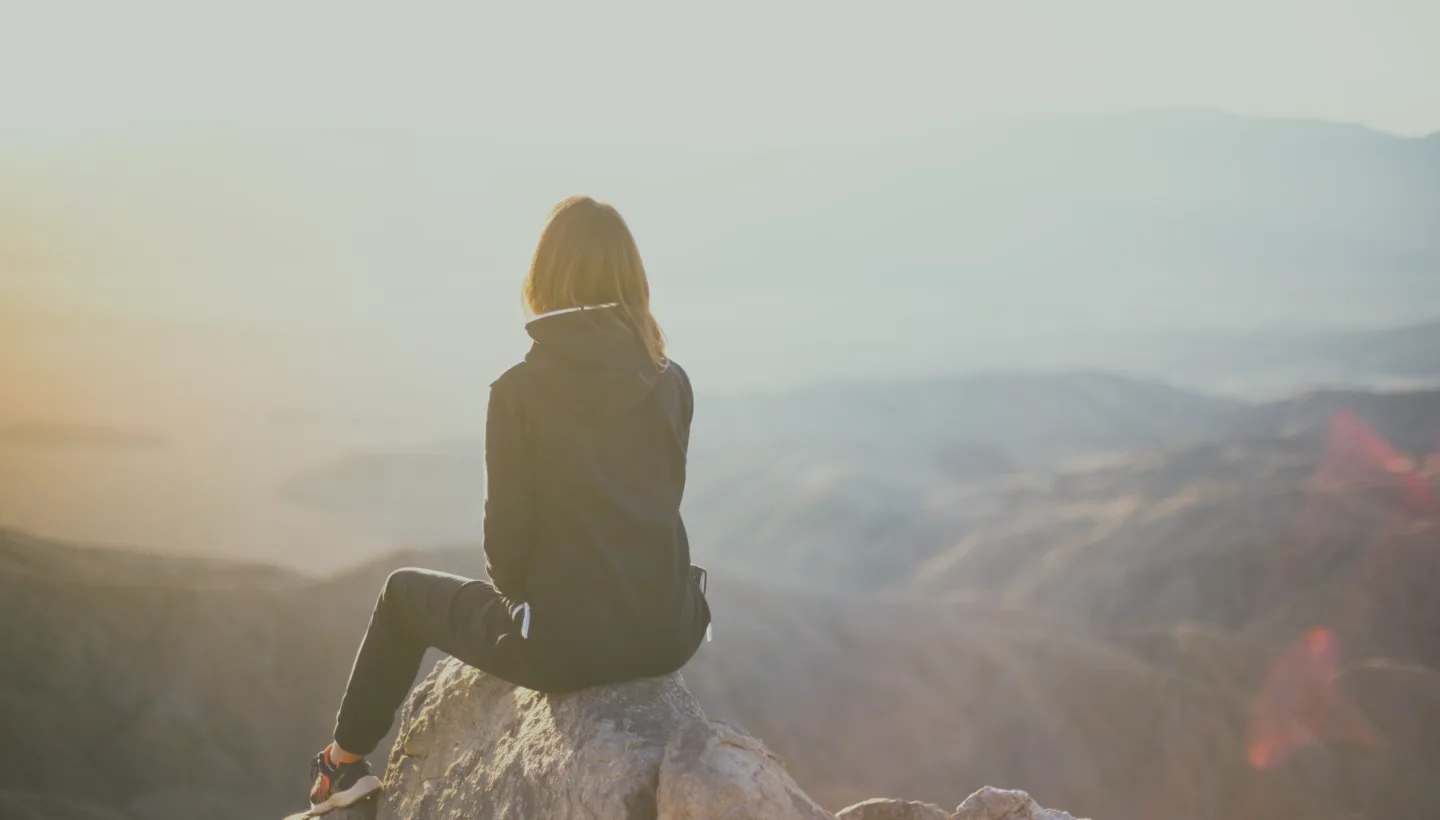 Person sitting on rock, sunset view